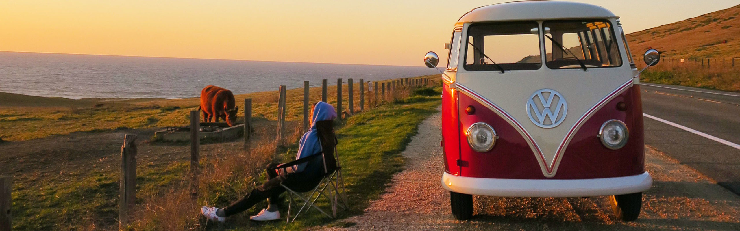 person sitting outside volkswagen van on coast