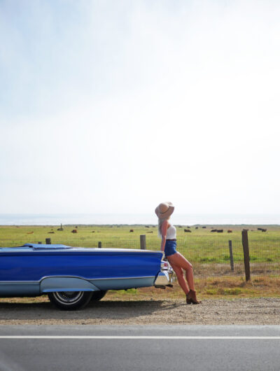 woman leaning on vintage car in big sur