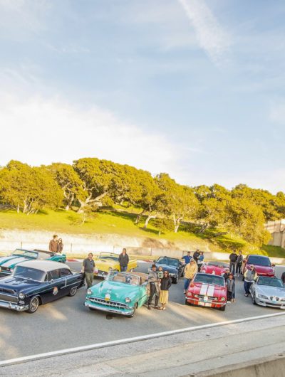 people with vintage cars at road rally