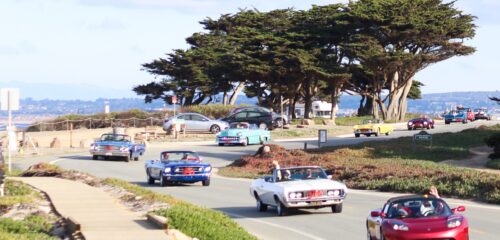 row of classic cars along coast at road rally